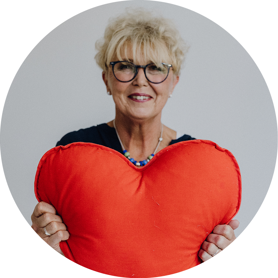 Diabetesberaterin DDG Barbara Müller hält lächelnd ein rotes Herz in die Kamera.