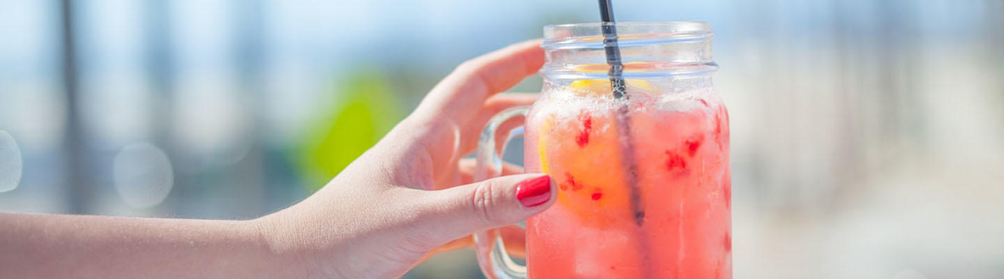 Frau greift nach einem Glas Limonade, um einer Hypoglykämie entgegenzuwirken.