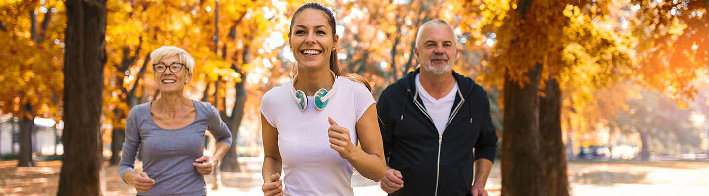 Eine kleine Gruppe von Menschen mit Diabetes treibt Sport unter herbstlichen Bäumen.