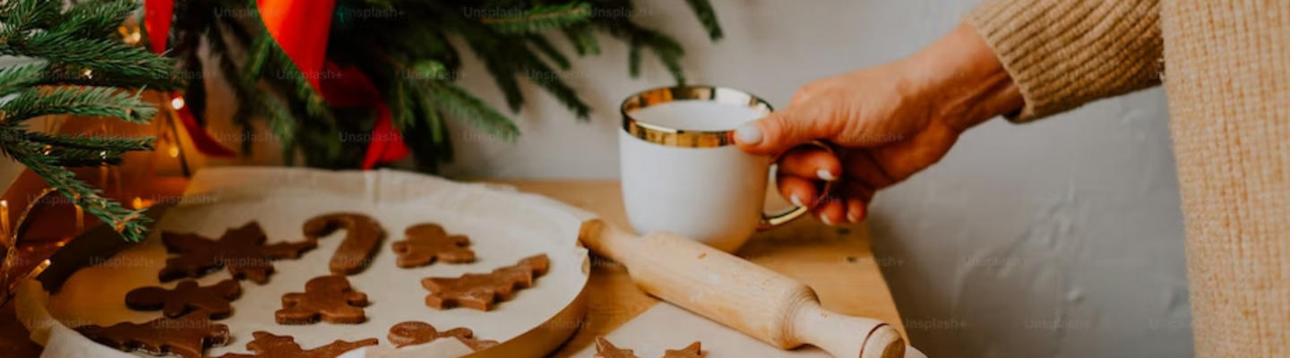 Frau mit Diabetes backt für Weihnachten Plätzchen, während sie eine Tasse Glühwein trinkt.