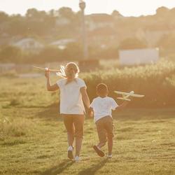 Diabetes bei Kindern: 2 Kinder rennen mit Flugzeugen über eine Wiese.