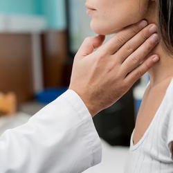 Zusammenhang zwischen Diabetes und der Schilddrüse: Arzt tastet Hals einer Frau ab.