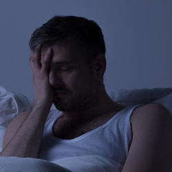 Mann mit Diabetes liegt nachts wach im Bett und leidet unter einer Schlafstörung.