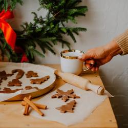 Frau mit Diabetes backt für Weihnachten Plätzchen, während sie eine Tasse Glühwein trinkt.