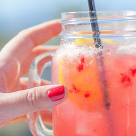 Frau greift nach einem Glas Limonade, um einer Hypoglykämie entgegenzuwirken.