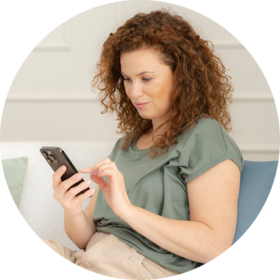 Frau mit CGM-Sensor am Arm hält einen Applikator und hat auf ihrem Smartphone die Accu-Chek SmartGuide App.