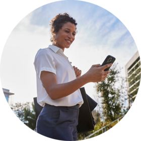 Frau steht im Freien und schaut auf ihr Smartphone mit der Accu-Chek SmartGuide App