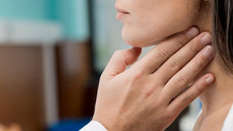 Zusammenhang zwischen Diabetes und der Schilddrüse: Arzt tastet Hals einer Frau ab.