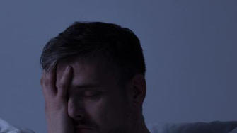 Mann mit Diabetes liegt nachts wach im Bett und leidet unter einer Schlafstörung.