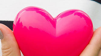 Bei Diabetes ist das Risiko für Schlaganfall und Herzinfarkt erhöht: Frau hält sich ein Herz aus Plastik vor die Brust.