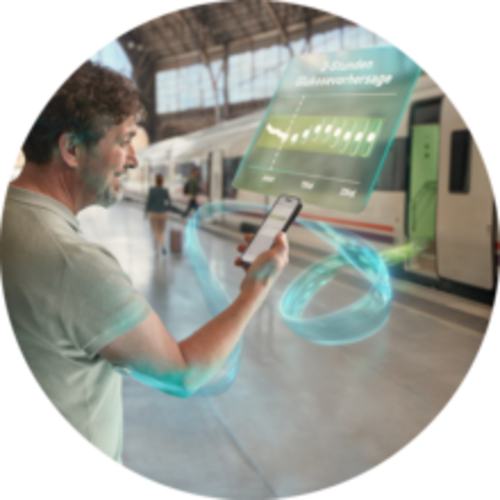 Mann steht an einem Bahnhof und schaut auf sein Smartphone, umgeben von digitalen, KI- visualisierten Datenprojektionen.